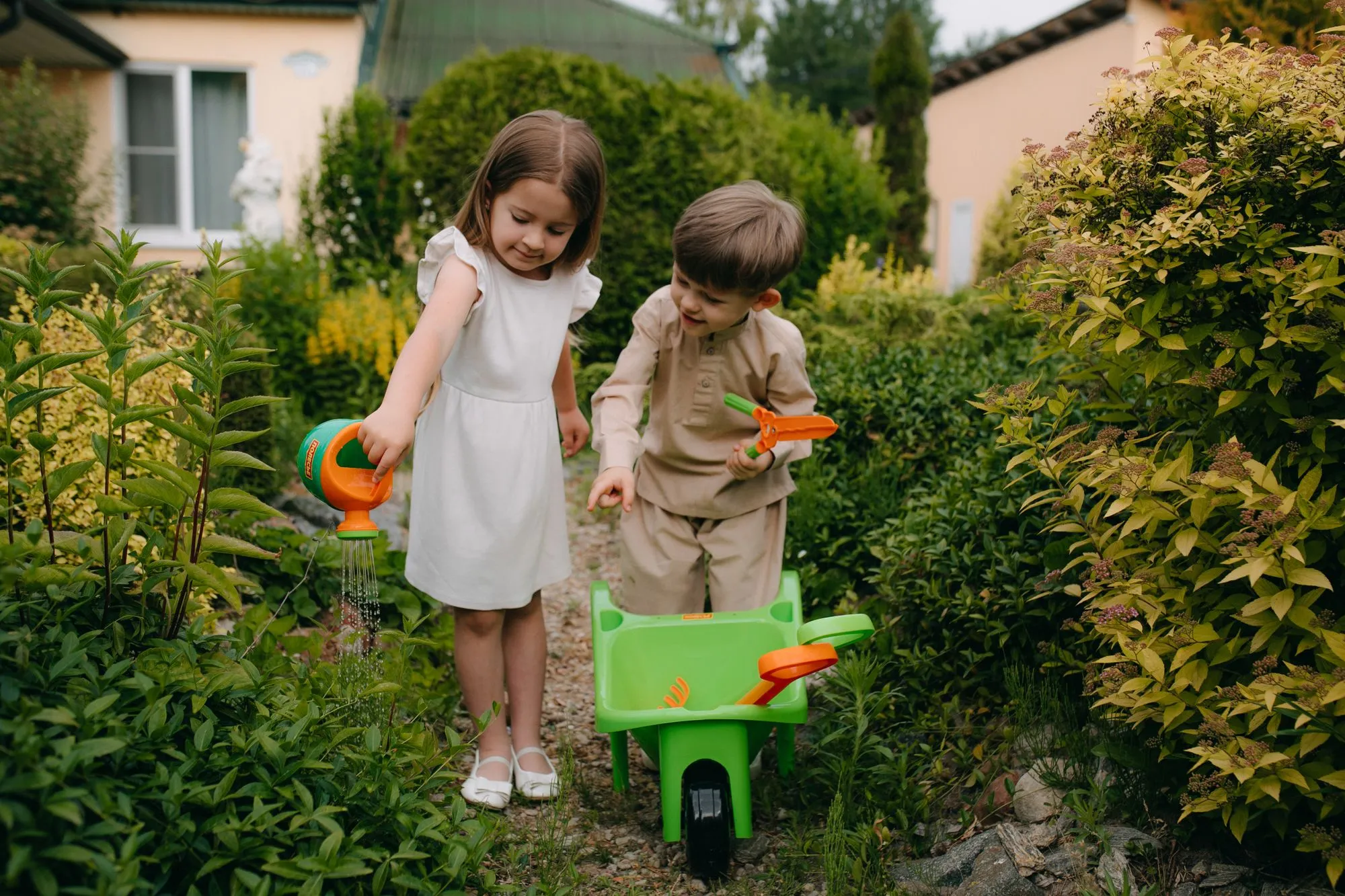 Twee kinderen spelen met een gieter in een tuin
