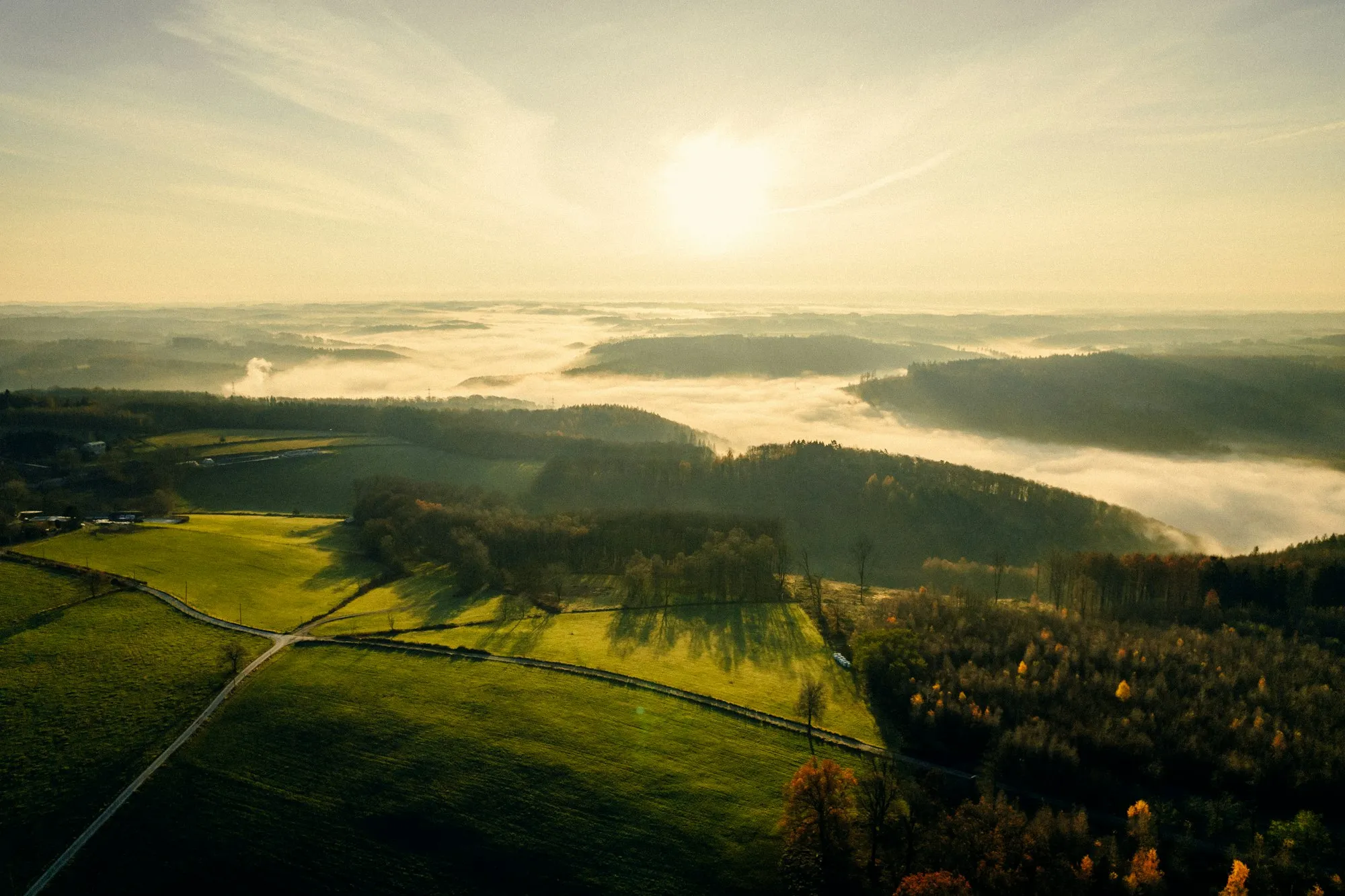 Zon boven een groene vallei met ochtendnevel in het Sauerland