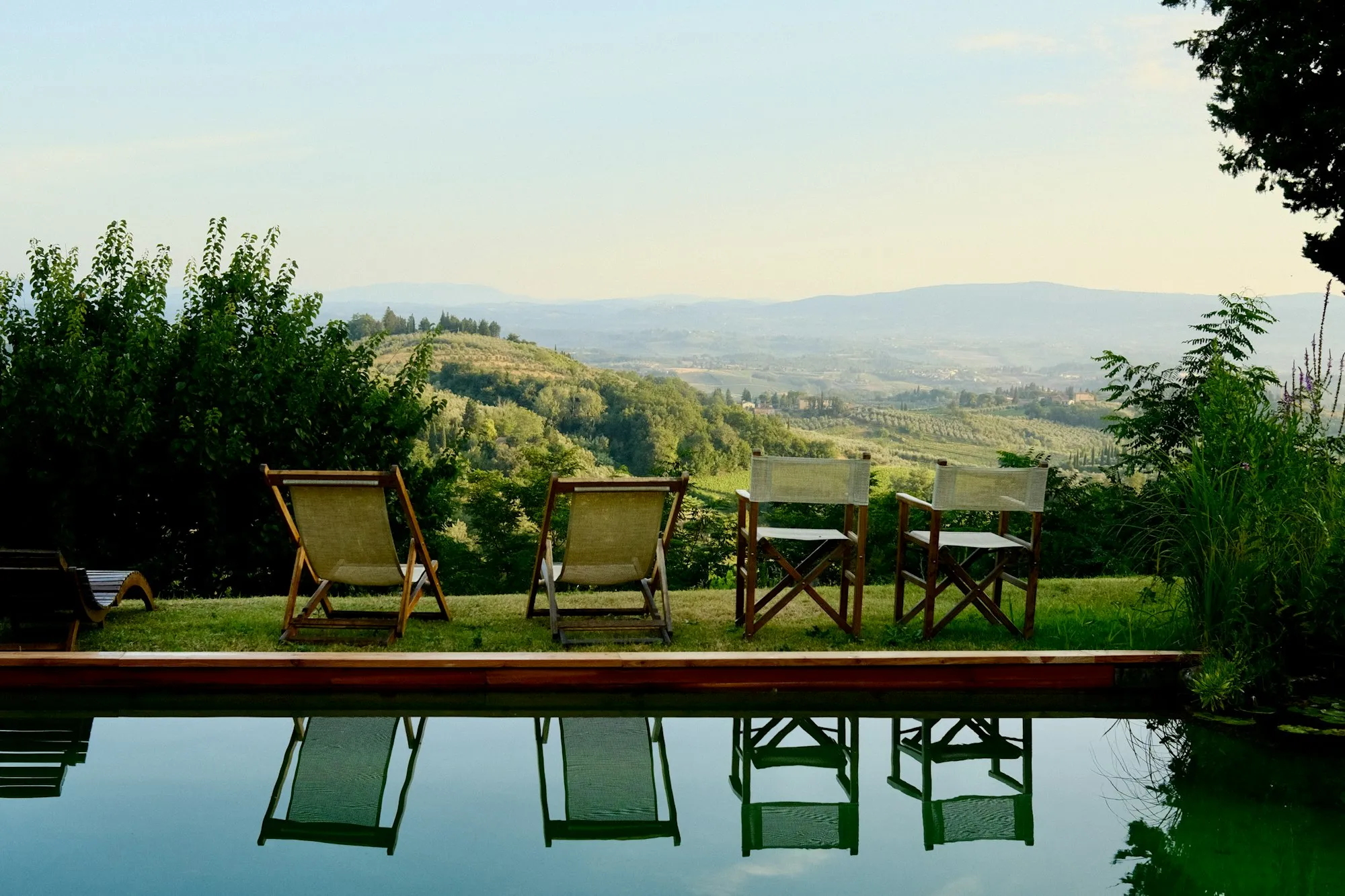 Vier stoelen aan een zwembad met uitzicht over de heuvels bij Certaldo in Toscane